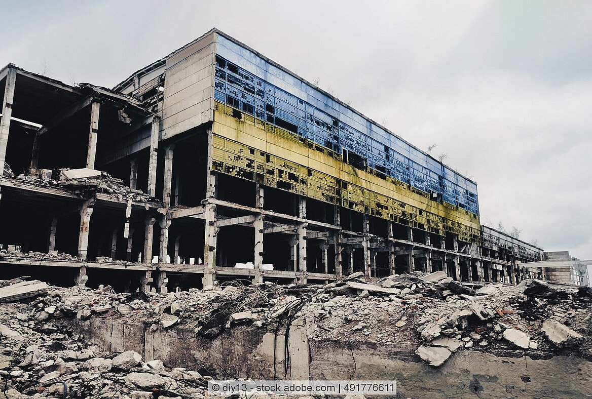 Ein Zerbombtes Gebäude mit einer Ukraine-Flagge.