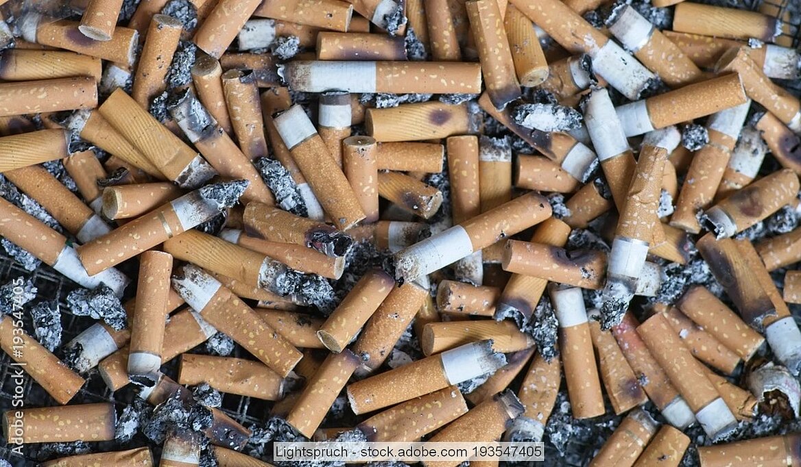 Zahlreiche Zigarettenkippen und Asche liegen durcheinander