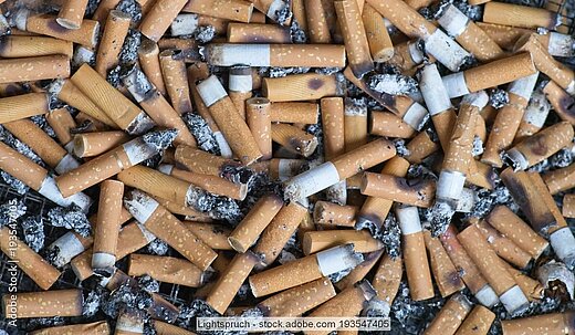 Zahlreiche Zigarettenkippen und Asche liegen durcheinander