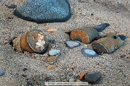 Teilweise verrostete Altmunition auf Meeresboden zwischen Sand und Steinen