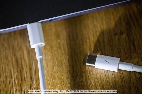 Apple-Ladekabel in Macbook auf Holzuntergrund