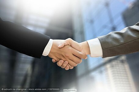 Symbolbild mit Handschlag von zwei Geschäftsleuten