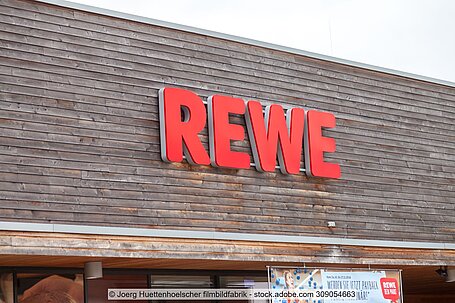Roter Rewe-Schriftzug an Außenwand von Supermarkthalle