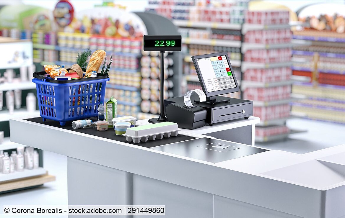 Kasse im Supermarkt, mit gefülltem Einkaufskorb und weiteren Produkten auf Laufban