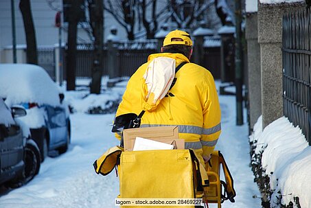 Postbote in verschneiter Straße