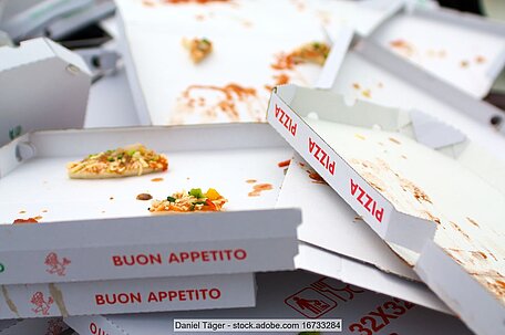 Haufen von weißen Pizzakartons mit roter Aufschrift, teilweise mit Essensresten