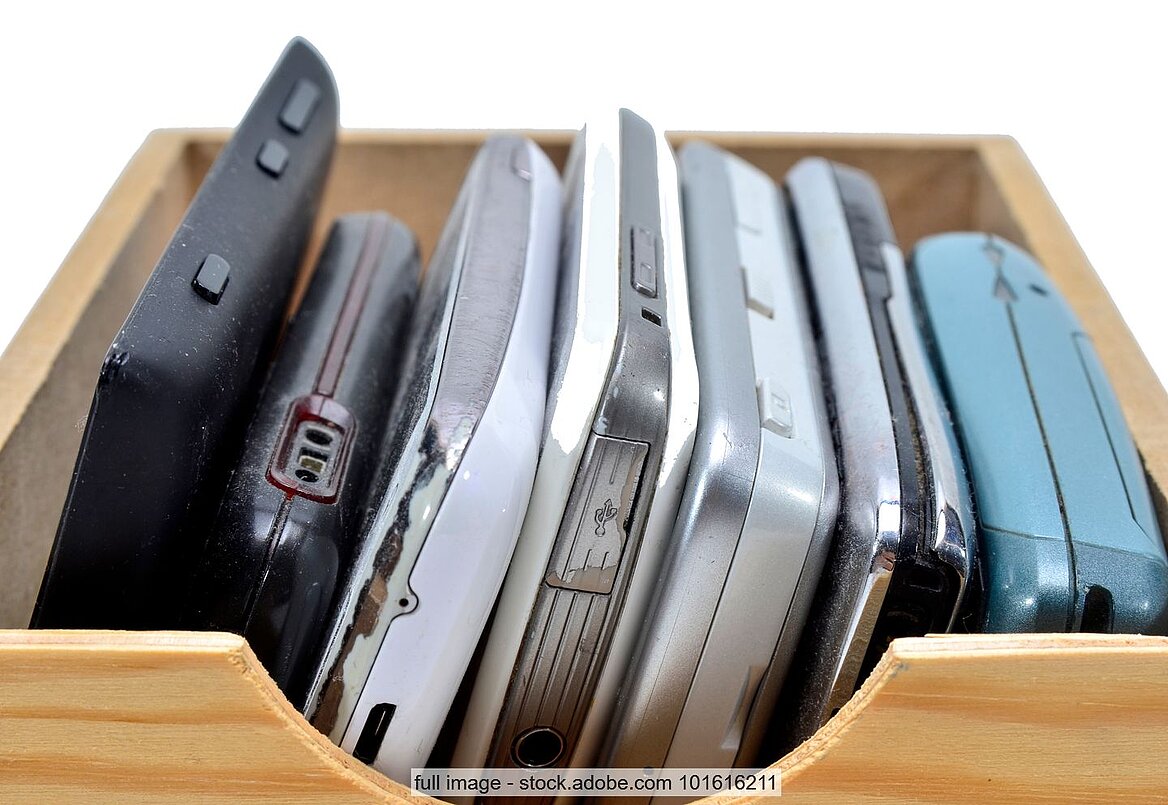 Smartphones und alte Mobiltelefone in Holzschublade