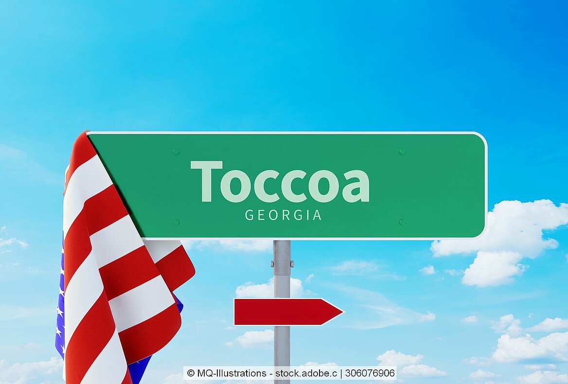 Die Flagge der USA hängt am Ortsschild von Toccoa im Bundesstaat Georgia.
