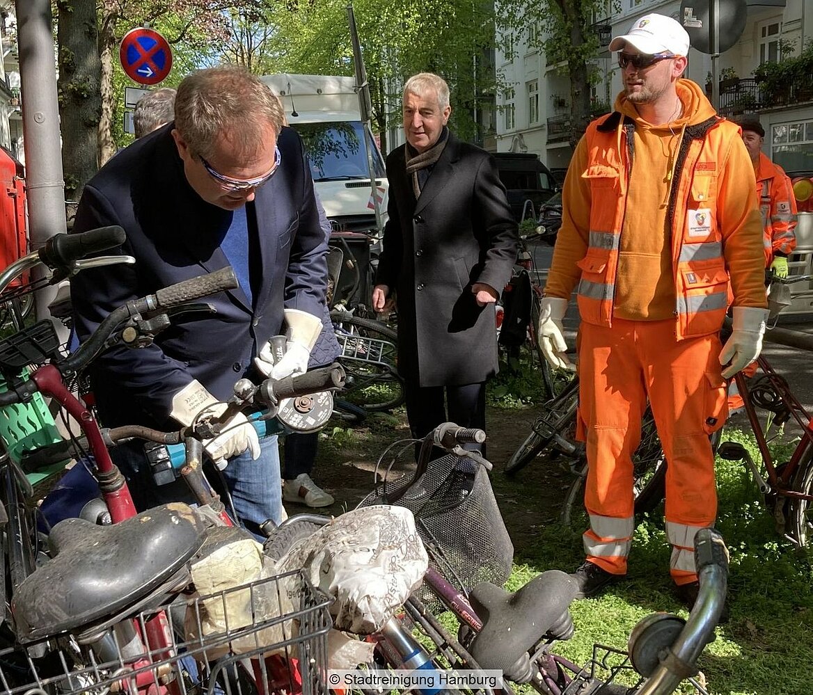 Alte Fahrräder werden mit einer Flex von Fahrradständern entfernt, im Hintergrund SRH-Geschäftsführer Rüdier Siechau
