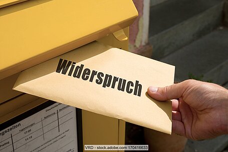 Briefumschlag mit Aufdruck "Widerspruch" wird in Postbriefkasten geworfen