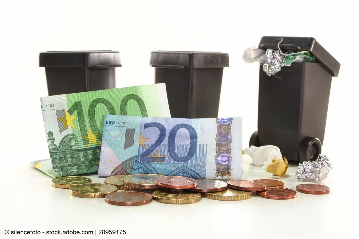Geldscheine und Münzen vor Spielzeug-Mülltonnen