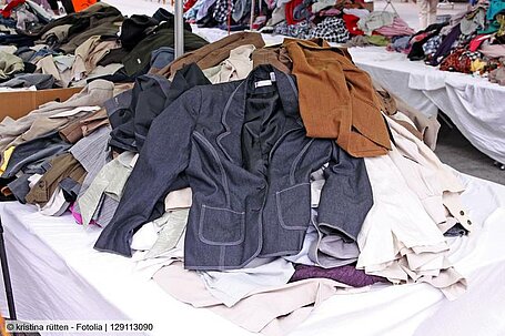 Mehrere Tische mit Haufen von verschiedenen gebrauchten Kleidungsstücken