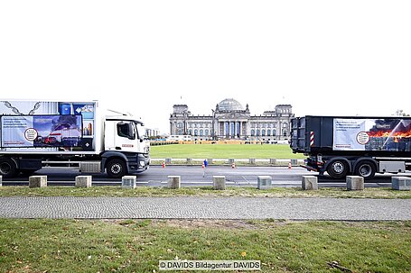 Müllwagen mit Bildern von Brandereignissen, im Hintergrund Reichstagsgebäude in Berlin