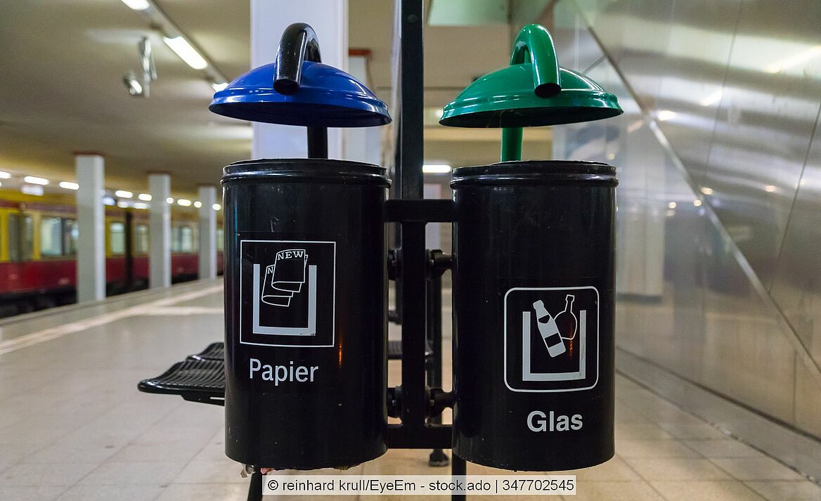 Zwei Mülleimer hängen in einem Bahnhof.