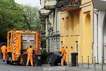 Müllwagen und Mitarbeiter der BSR mit Mülltonnen auf Straße vor Wohnhaus in Berlin