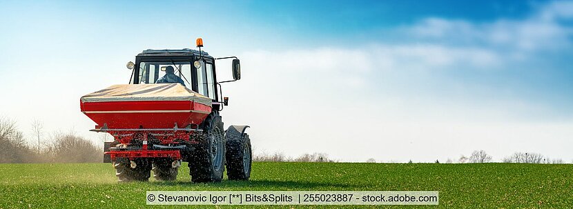 Dünger Traktor auf grüner Wiese mit blauem Himmel