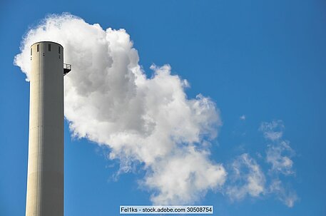 Symbolbild von Schornstein mit Dampffahne vor blauem Himmel