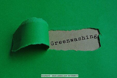 Aufgerissenes grünes Papier mit Schriftzug "Greenwashing" darunter