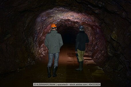 Zwei Männer laufen durch einen Schacht im Untertagebau.