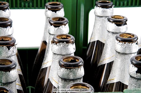 Leere Bierflaschen mit silbernem Etikett in grüner Kiste