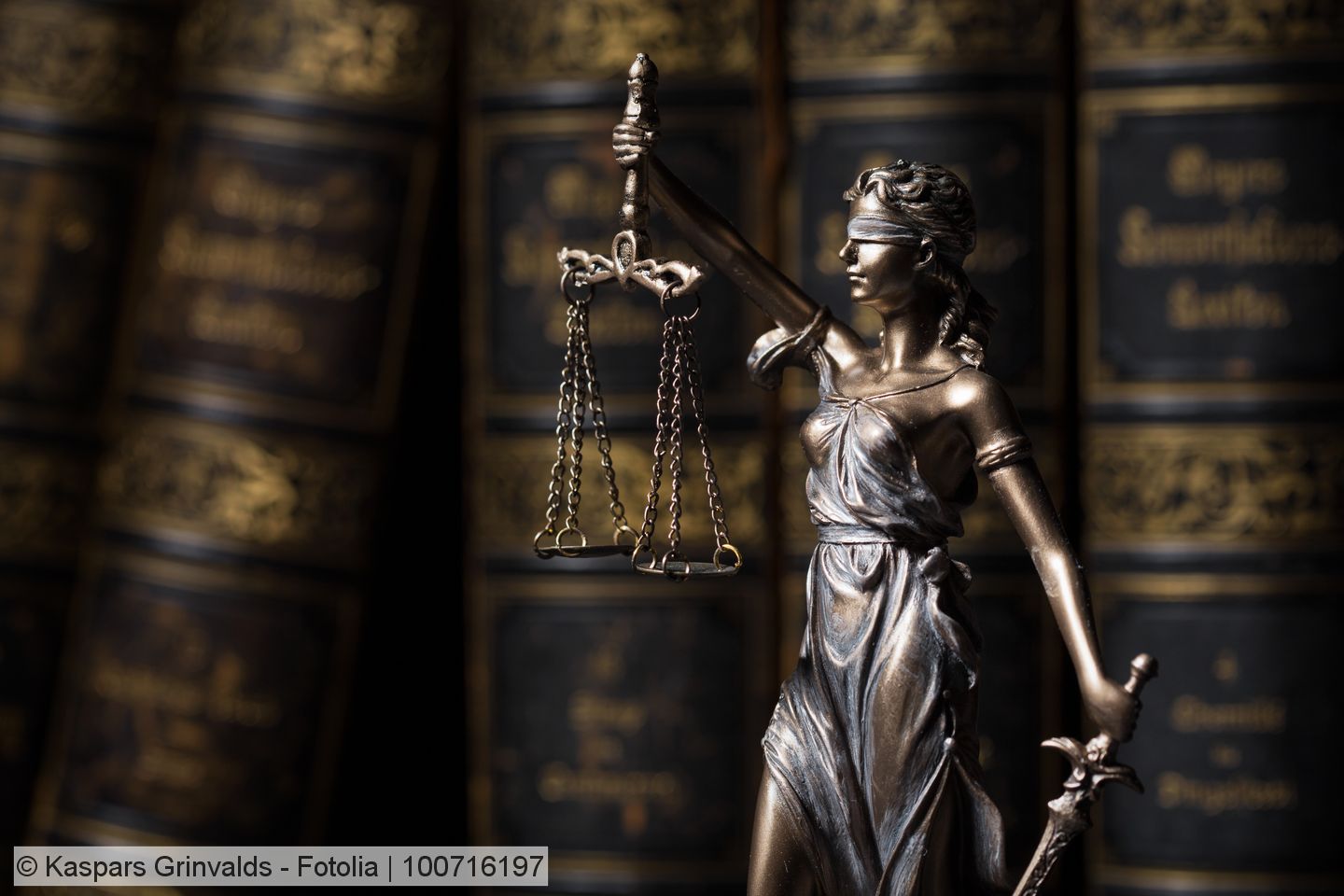 Metallene Figur der Justizia vor alten Gesetzbüchern