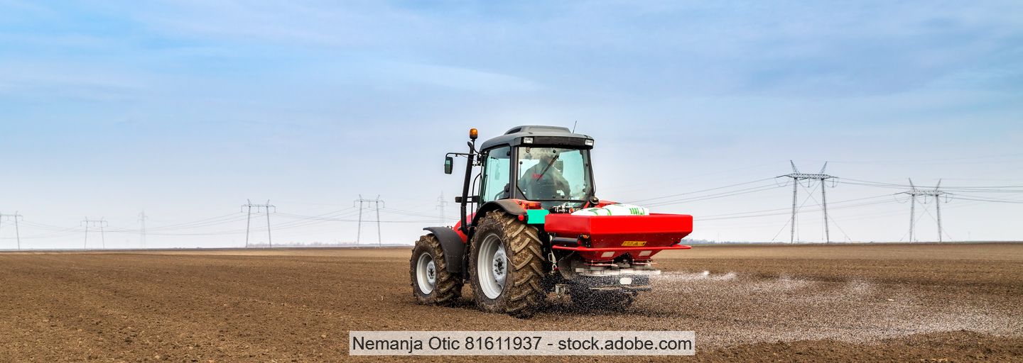 Ein Bauer düngt sein Feld mit einem Traktor