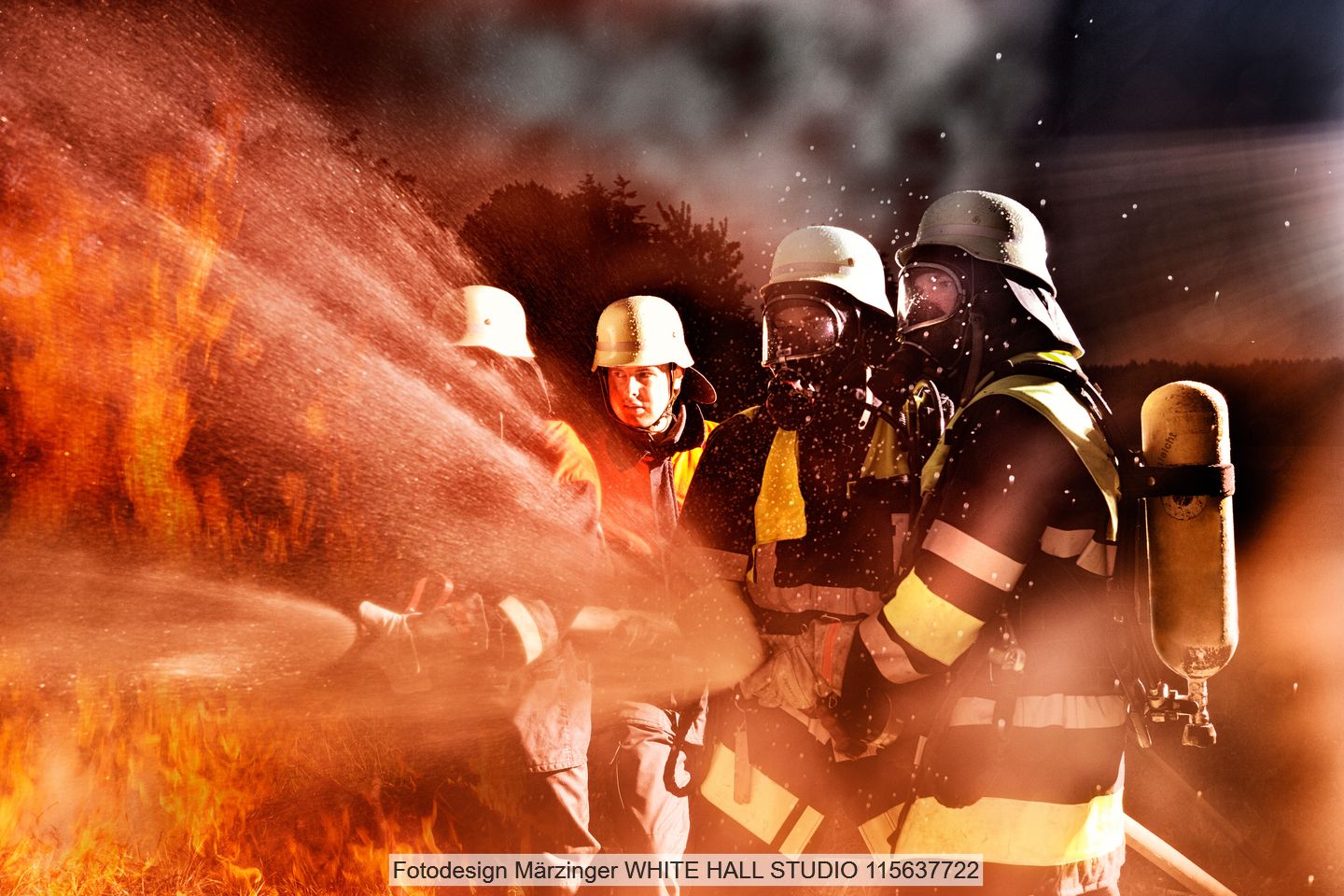 Drei Feuerwehrmänner versuchen ein Feuer zu bekämpfen und halten Schläuche in ihren Händen.