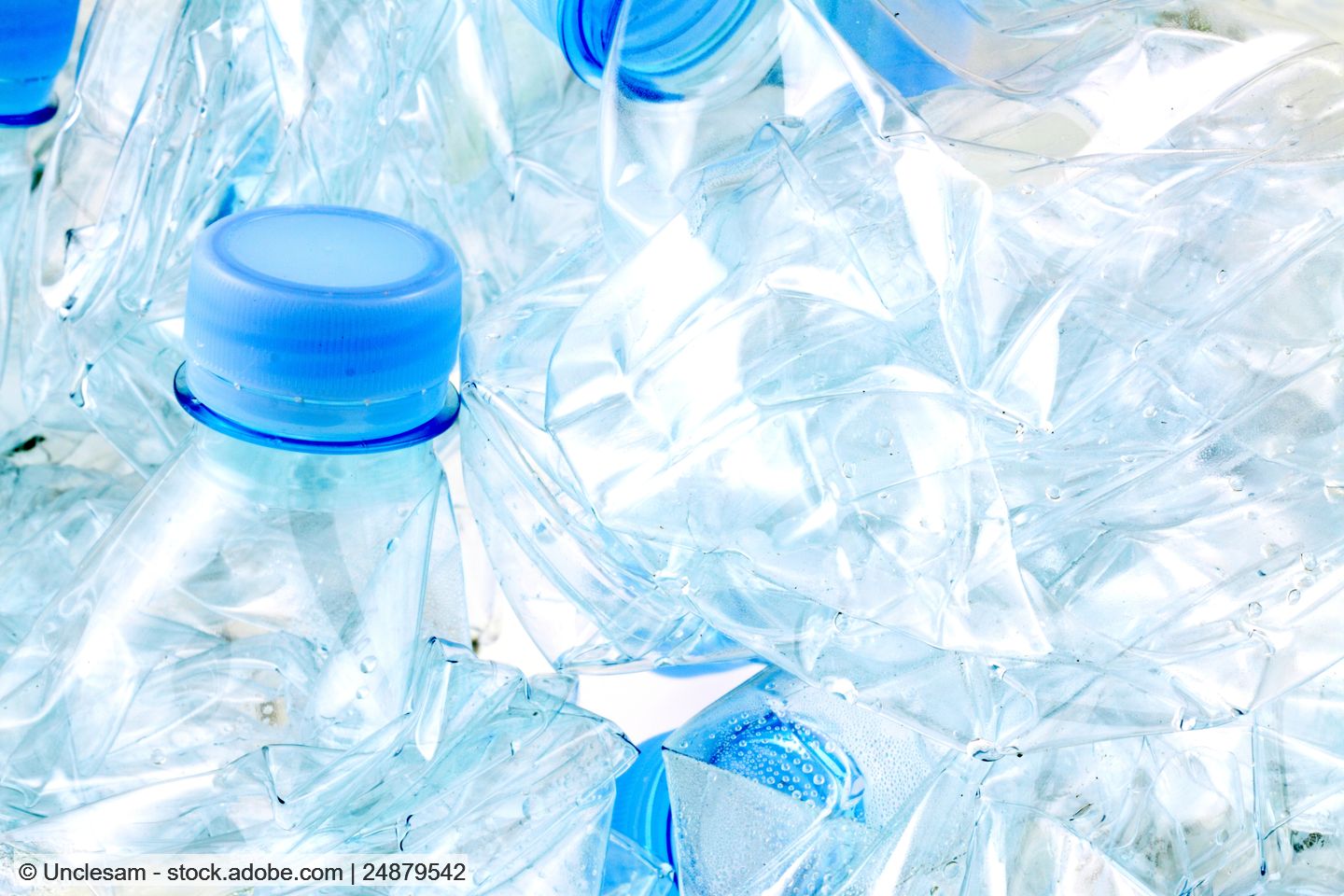 Mehrere zerdrückte klare PET-Flaschen mit hellblauen Verschlüssen