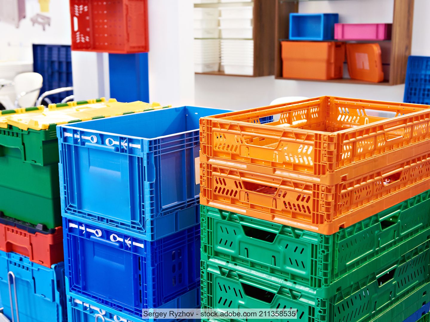 Gestapelte Transportkisten aus Kunststoff in verschiedenen Formen und Farben in einem Lagerraum.