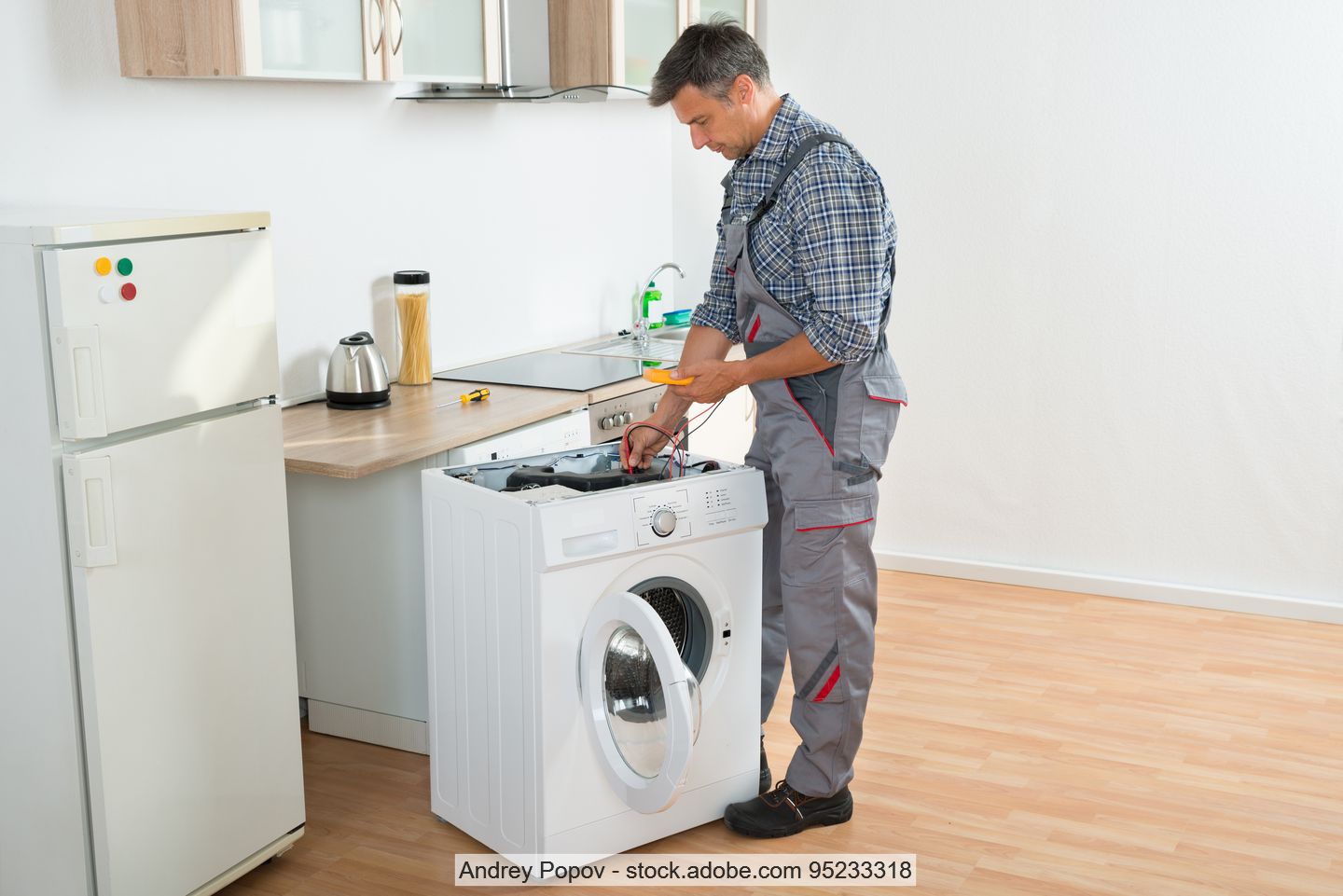 Techniker in Küche bei Reparatur von Waschmaschine