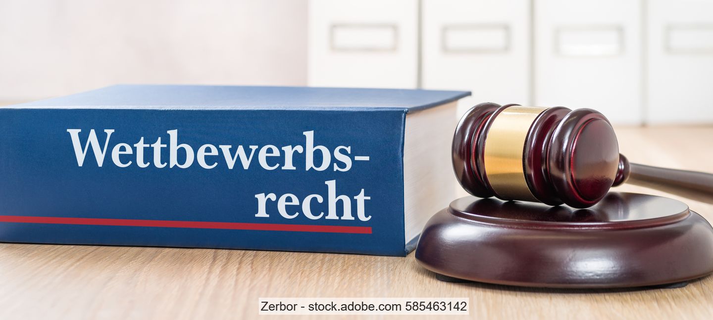 Buch mit Aufschrift "Wettbewerbsrecht" neben Richterhammer auf Holztisch